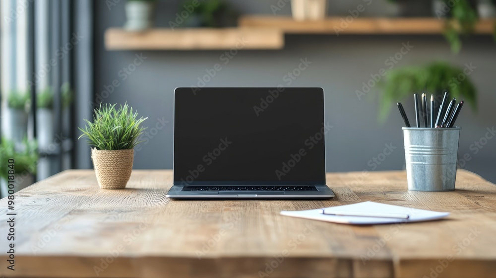 Fototapeta premium Minimalistic office workspace with laptop, pen, and notepad on a wooden desk in soft natural light