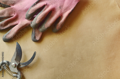 gardening themed, planting table, flat lay, secateurs pink working gloves, beige wrapping paper covered table, top view, copy space,