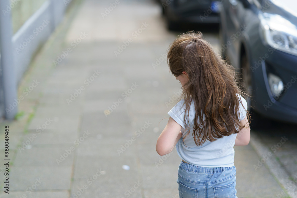 Little preschool girl with long long blond hair walks with her back to the camera on the sidewalk of a European city. Children's travel concept Little preschool girl with long long blond hair walks with her back to the camera on the sidewalk of a European city. Children's travel concept