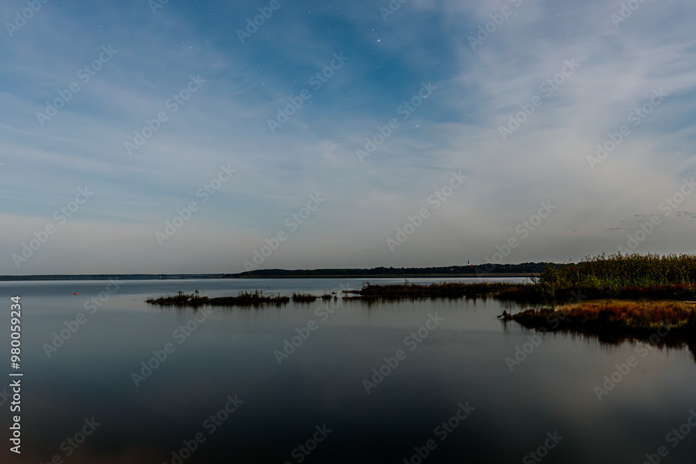 A tranquil lake at dusk, with small boats lined along the shore. The smooth water reflects the evening sky, filled with soft clouds and a few stars. The calm atmosphere creates a peaceful A tranquil lake at dusk, with small boats lined along the shore. The smooth water reflects the evening sky, filled with soft clouds and a few stars. The calm atmosphere creates a peaceful