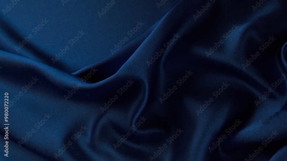 Obraz premium A close-up shot of deep blue fabric with soft, natural folds and wrinkles, showcasing its smooth texture and rich color. Ideal for fashion, textiles, or backgrounds