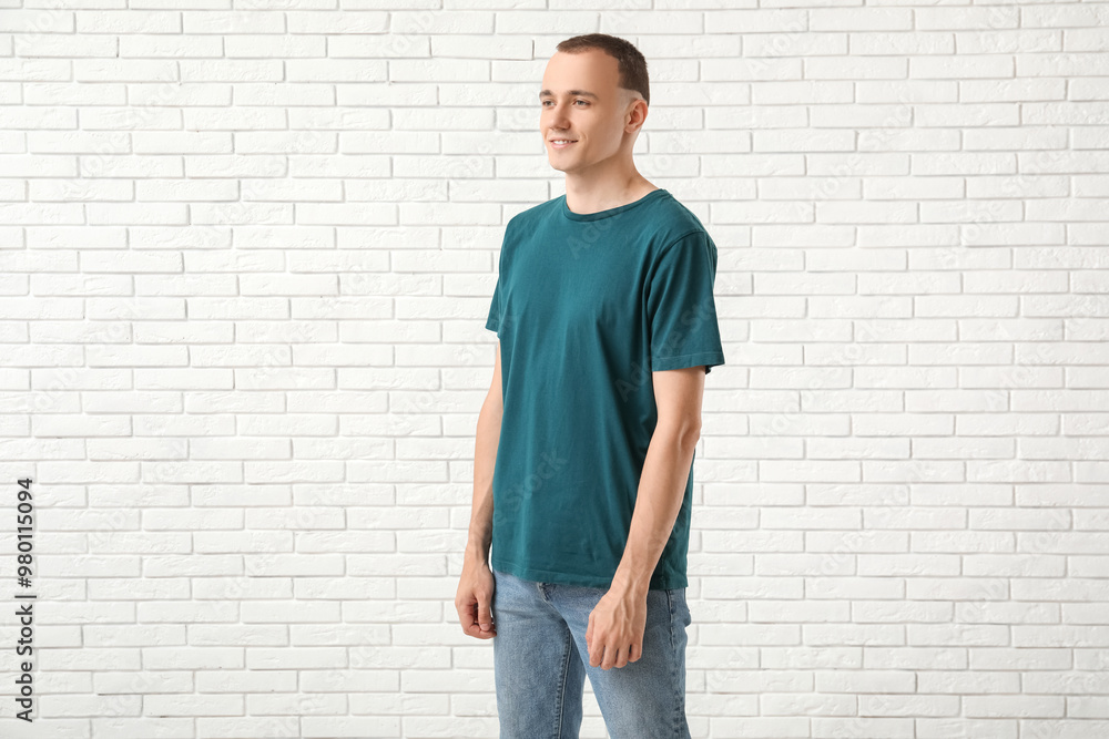 Handsome young man in stylish t-shirt near white brick wall Handsome young man in stylish t-shirt near white brick wall