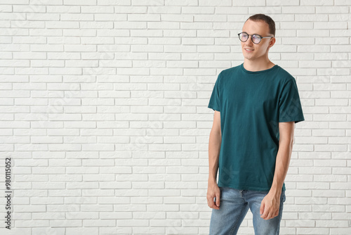 Handsome young man in stylish t-shirt near white brick wall