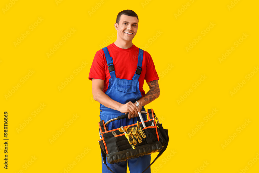 Male car mechanic taking wrench from tools bag on yellow background Male car mechanic taking wrench from tools bag on yellow background