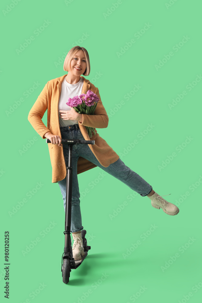 Beautiful mature happy woman with kick scooter and bouquet of tulips on green background Beautiful mature happy woman with kick scooter and bouquet of tulips on green background