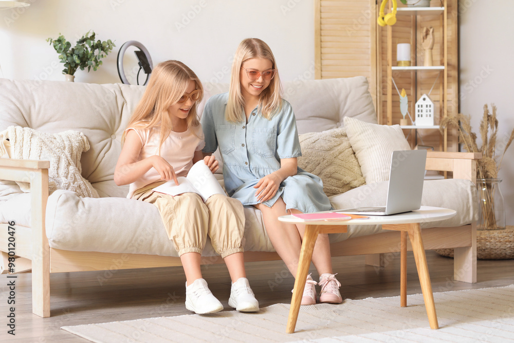 Female blogger with her daughter recording video while unpacking parcel at home Female blogger with her daughter recording video while unpacking parcel at home