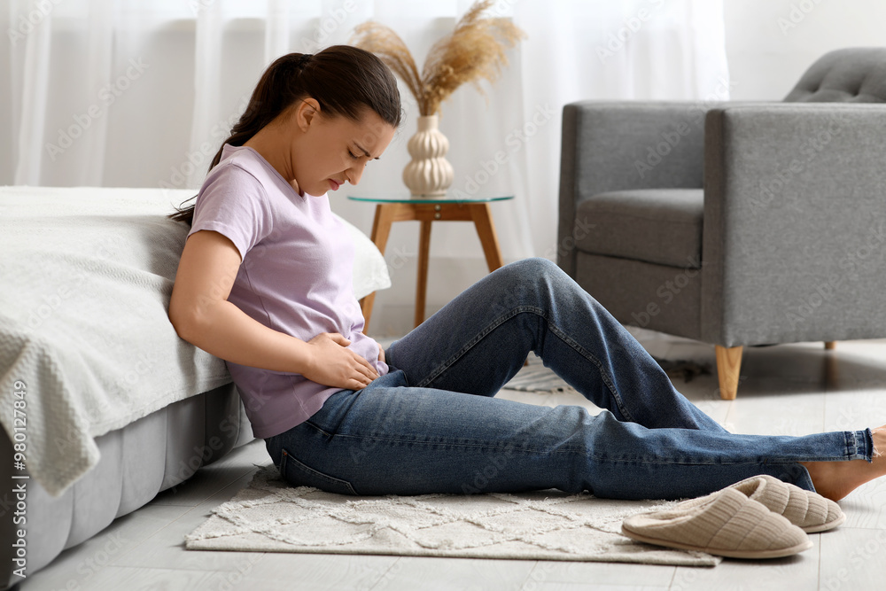Young woman suffering from cystitis on floor in bedroom Young woman suffering from cystitis on floor in bedroom