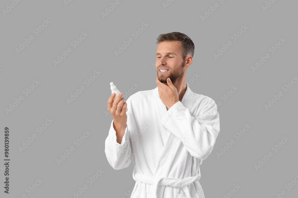 Handsome young man with cosmetics for beard on grey background Handsome young man with cosmetics for beard on grey background