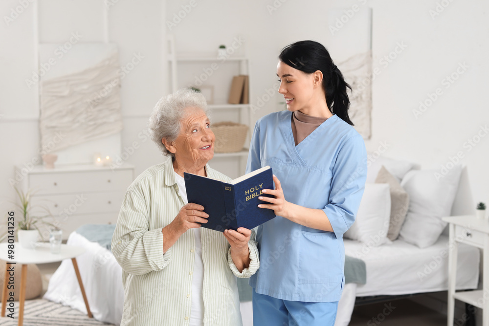 Obraz premium Caregiver and senior woman reading Bible at home