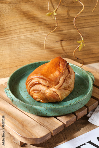 Close up of delicious almond croissants on a wooden plate with linen and flowers, bathed in soft light on a wooden surface. Perfect for bakery or foodthemed designs. photo