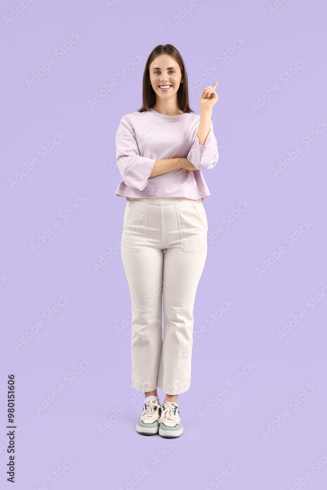 Young woman pointing at something on lilac background Young woman pointing at something on lilac background