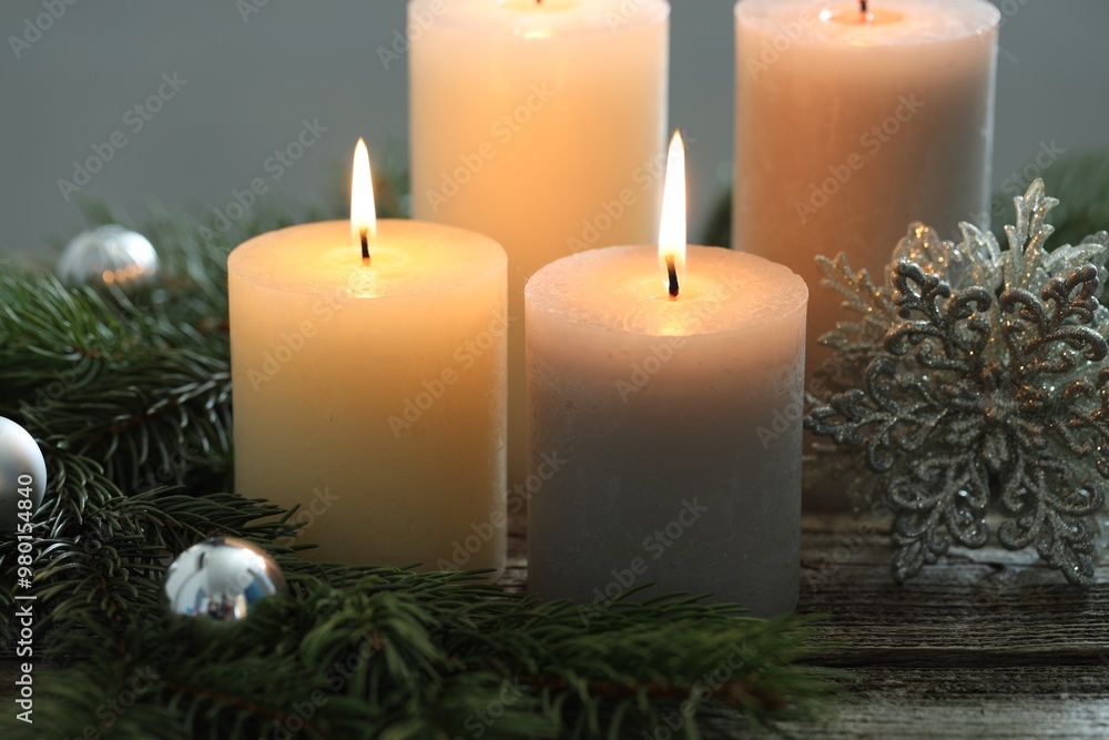 Burning candles, baubles and fir tree branches on wooden table, closeup Burning candles, baubles and fir tree branches on wooden table, closeup