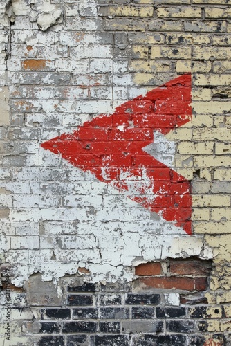 A bold red arrow icon painted on a crumbling brick wall, symbolizing persistence in the face of obstacles. 