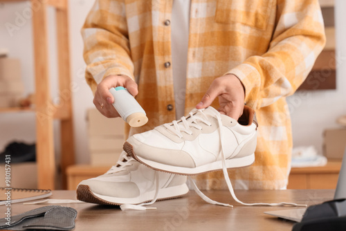 Male shoemaker polishing sneaker in repair shop, closeup photo