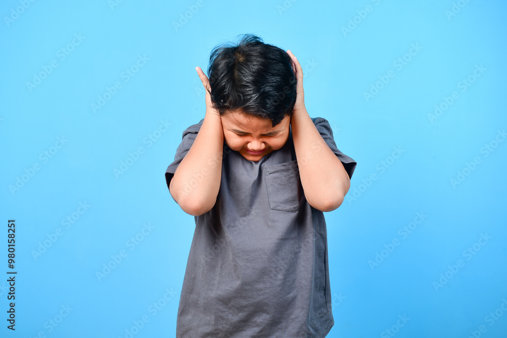 Scared boy standing and covering his ear with hand Scared boy standing and covering his ear with hand