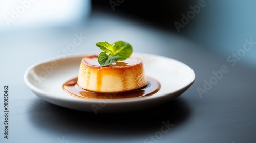 Delicious flan dessert with caramel sauce and mint garnish presented on a white plate at a cozy cafe background.