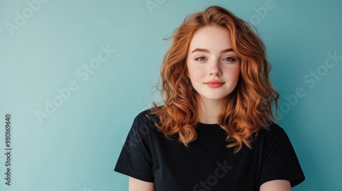 Portrait of a young woman with red curly hair against a teal background, exuding confidence and warmth in a casual attire.