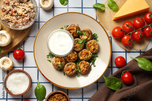 Stuffed mushrooms on plate, sauce and ingredients on light background, top view