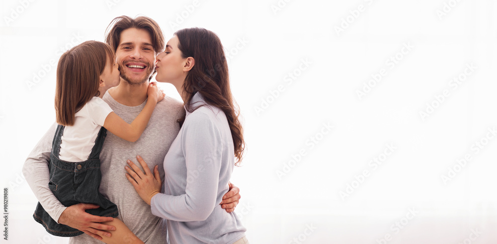 Sweetest kiss. Wife and daughter kissing happy man on both cheeks while standing together against window at home, copy space Sweetest kiss. Wife and daughter kissing happy man on both cheeks while standing together against window at home, copy space