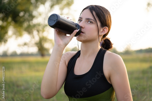 A shaker in the hand of a girl as a desire for healthy nutrition and attention to her body after hard training, yoga. Concept: nutrients, recovery, sports equipment.