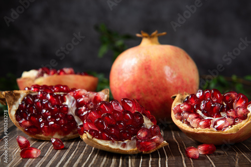 open pomegranates, and pomegranate seeds on wooden table.