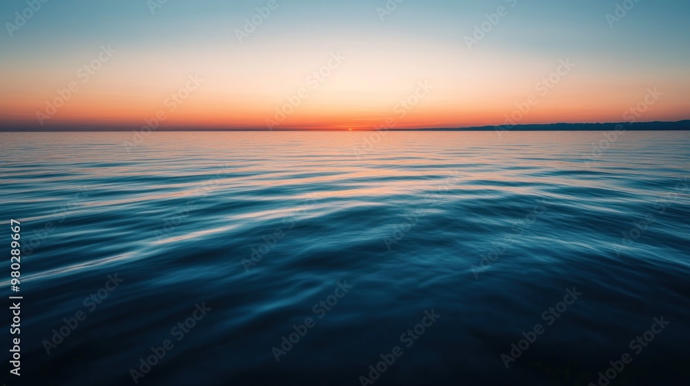 Fototapeta premium Waves gently kiss the shore as the sun sets in peace.