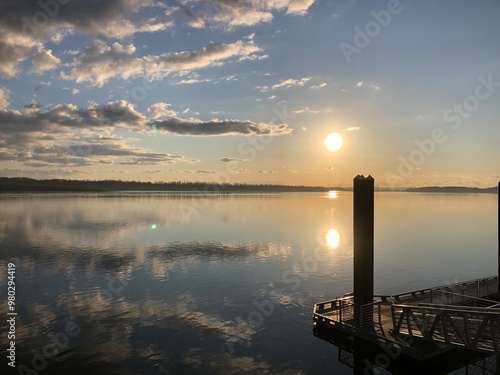 View of a sunset on the Columbia River with clouds reflecting off the water and a dock in the foreground