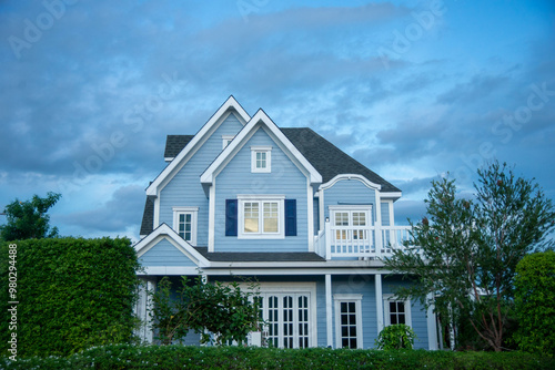 American cottage style house with expensive trees surrounding it.