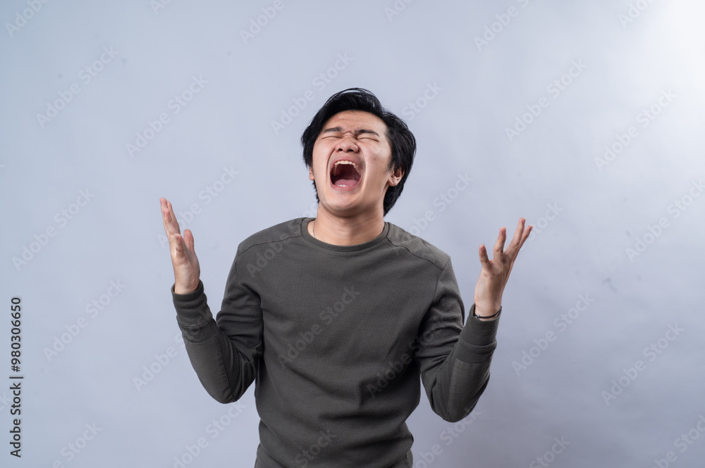 An Asian man is looking upwards with an exasperated expression, his hands raised in frustration or confusion. He is wearing a dark long-sleeve shirt, with a plain white background An Asian man is looking upwards with an exasperated expression, his hands raised in frustration or confusion. He is wearing a dark long-sleeve shirt, with a plain white background