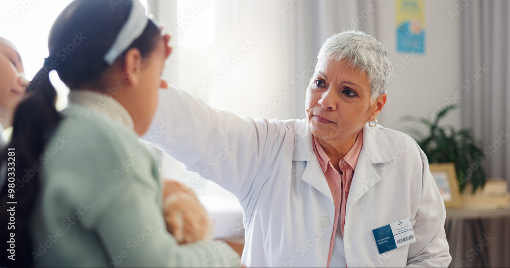 Obraz premium Doctor, child and check fever at clinic, pediatrician and sick girl for healthcare assessment. Mature woman, helping kid and medic for physician diagnosis, touching head and hospital exam for flu