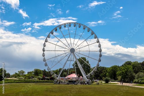 Stunning Large Ferris Wheel Set Against a Bright Blue Sky with Soft Fairy Clouds on a Beautiful Summer Day, Capturing the Joy and Whimsy of Amusement Parks