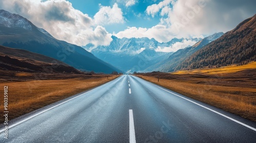 Scenic mountain road leading through vast and tranquil countryside landscape under dramatic cloudy sky