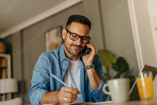 A focused, creative male writer typing and editing his work on a laptop while sitting at a table indoors