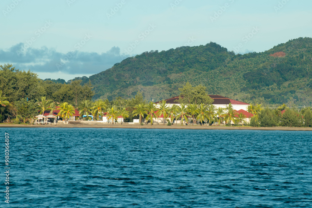 Fototapeta premium As the mountains stand tall in the port, the fishermen's boat sets sail.