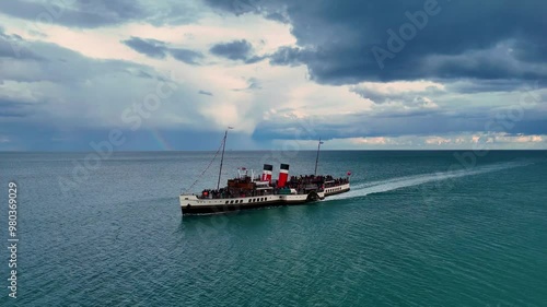 A breathtaking aerial view captures a graceful paddle steamer gliding serenely across calm seas, its vintage charm highlighted by the slow, sweeping motion of the camera. photo