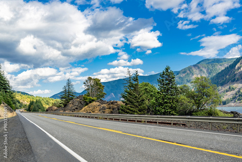 Summer highway road along the Columbia River with rocky mountains and evergreen trees on the sides