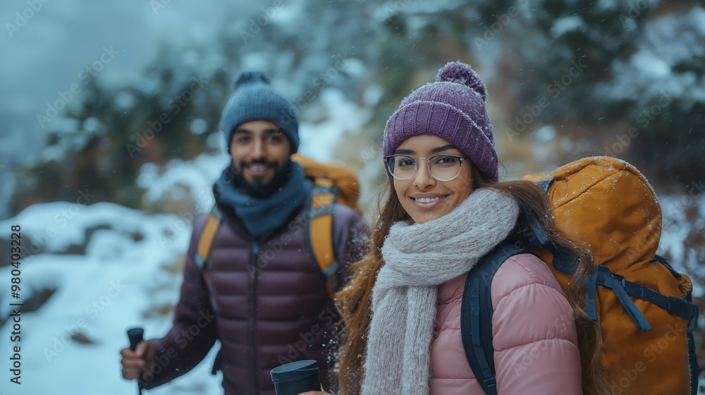 Fototapeta premium Smiling Hispanic Couple Hiking Through Snowy Mountains in Winter Gear, Enjoying Outdoor Adventure During Cold Season, Focus on Mountain Landscape