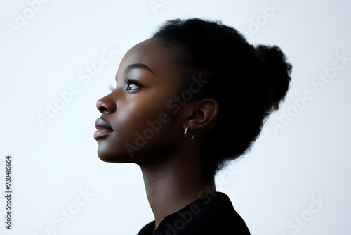 Side view portrait of a joyful African woman with glowing dark skin, captured in a close-up against a plain white background