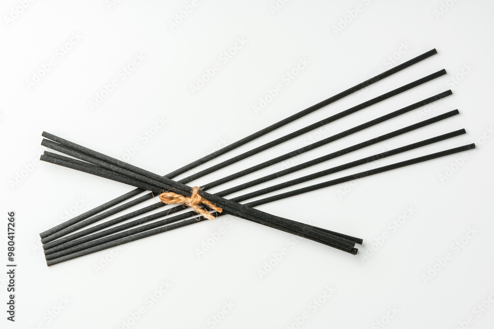 Black aromatic sticks resting on a plain white background Black aromatic sticks resting on a plain white background