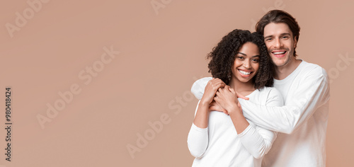 International love. Romantic multiracial couple embracing, posing together over yellow background in studio, copy space