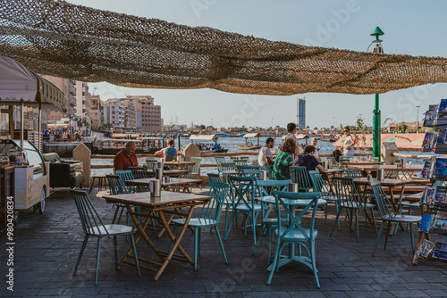 Canvas Print Dubai, UAE - January 6, 2020: Outdoor cafe seating along Dubai Creek with waterf