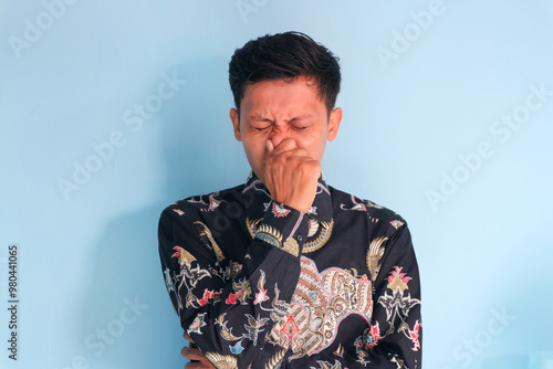 Young asian man covering nose and avoiding bad smell