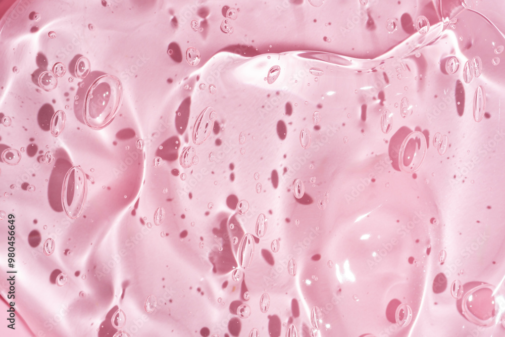 Cosmetic gel or beauty jelly serum texture background. Transparent skin care collagen product backdrop. Antibacterial sanitizer or liquid water moisture toner smudged smear close up photo on pink Cosmetic gel or beauty jelly serum texture background. Transparent skin care collagen product backdrop. Antibacterial sanitizer or liquid water moisture toner smudged smear close up photo on pink