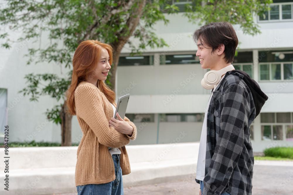 Fototapeta premium Attractive Asian college students using laptop, tablet, mobile phone to study online social media Finding knowledge together, talking, working as a team. Educational concept success in life.