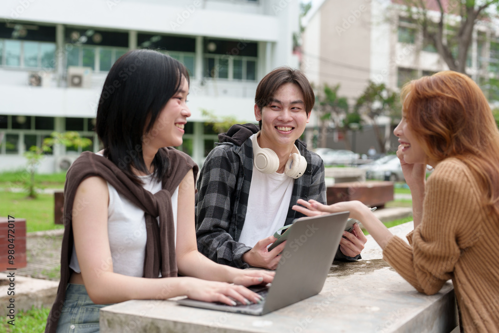 Fototapeta premium Attractive Asian college students using laptop, tablet, mobile phone to study online social media Finding knowledge together, talking, working as a team. Educational concept success in life.