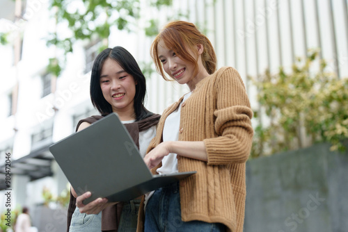 Attractive Asian college students using laptop, tablet, mobile phone to study online social media Finding knowledge together, talking, working as a team. Educational concept success in life.