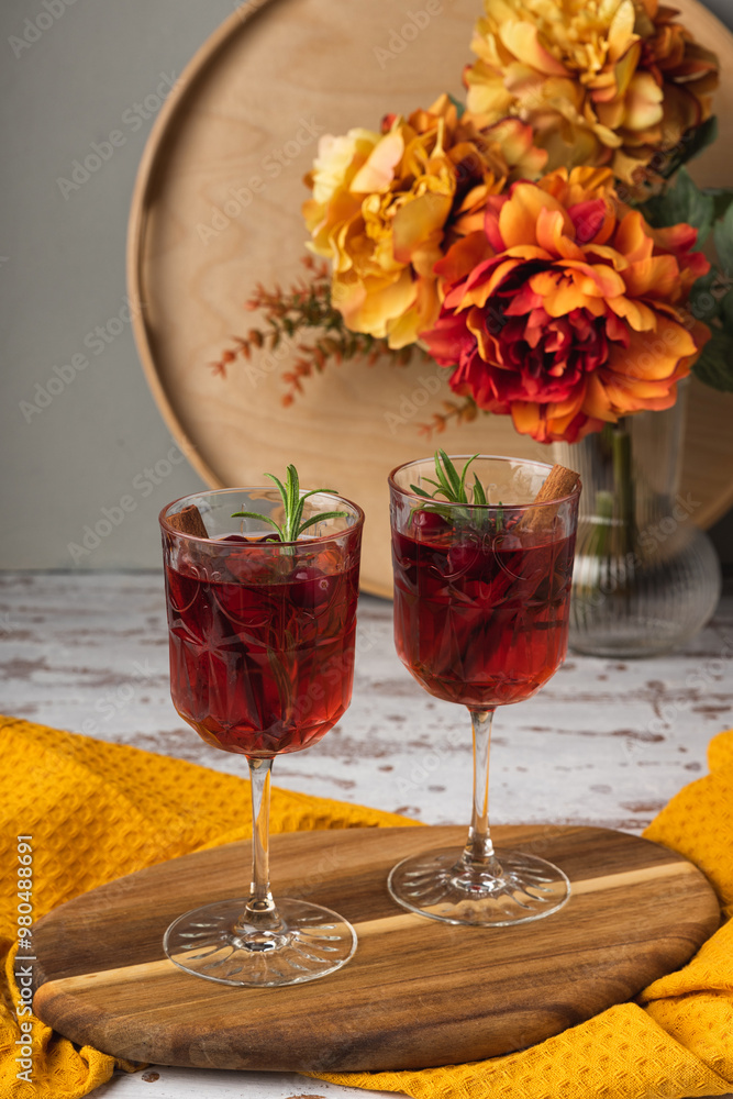 Autumn spiced cocktail with wine on a rustic holiday table. Homemade seasonal drink Sangria for Halloween, Thanksgiving with cinnamon and rosemary. Decorative textile pumpkins and candles Autumn spiced cocktail with wine on a rustic holiday table. Homemade seasonal drink Sangria for Halloween, Thanksgiving with cinnamon and rosemary. Decorative textile pumpkins and candles