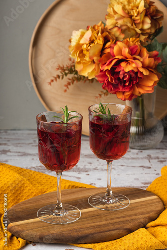 Autumn spiced cocktail with wine on a rustic holiday table. Homemade seasonal drink Sangria for Halloween, Thanksgiving with cinnamon and rosemary. Decorative textile pumpkins and candles photo