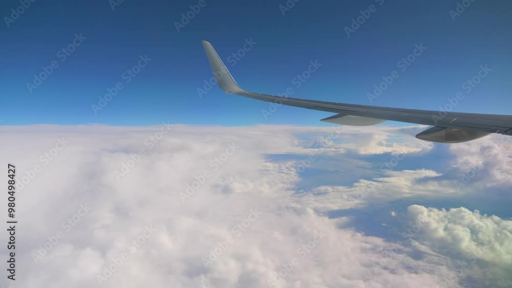 Airplane wing flying high above the clouds in a clear blue sky in 4k Airplane wing flying high above the clouds in a clear blue sky in 4k