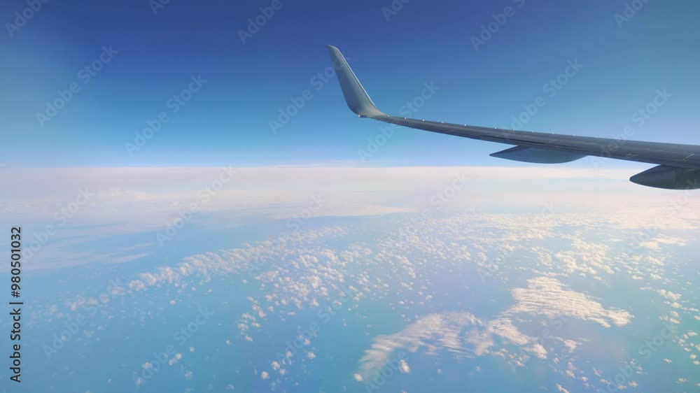 Airplane wing flying high above the clouds in a clear blue sky in 4k Airplane wing flying high above the clouds in a clear blue sky in 4k